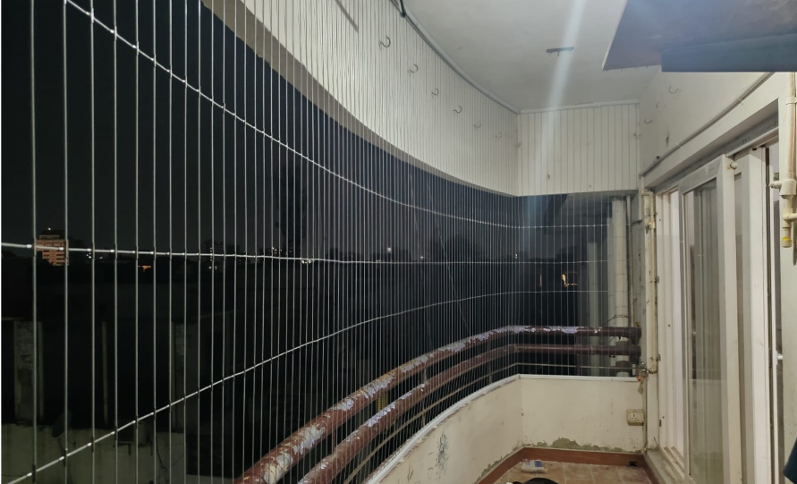 Curved apartment balcony protected with premium invisible grills providing safety without blocking the outside view.